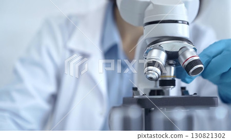 Scientist using microscope in laboratory. Close-up of a researcher's hands adjusting a modern microscope in a lab setting. Science concept Scientist using microscope in laboratory. Close-up of a researcher's hands adjusting a modern microscope in a lab setting. Science concept 130821302