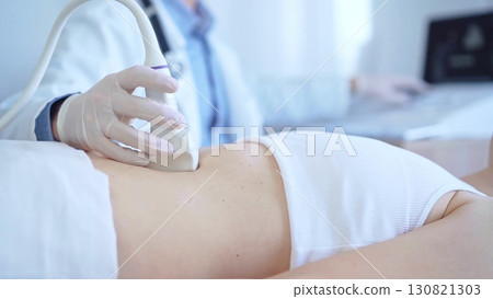 Doctor man wearing a white medical gloves using an ultrasound machine on a female patient examining internal organs, closeup vie. Medicine service Doctor man wearing a white medical gloves using an ultrasound machine on a female patient examining internal organs, closeup vie. Medicine service 130821303
