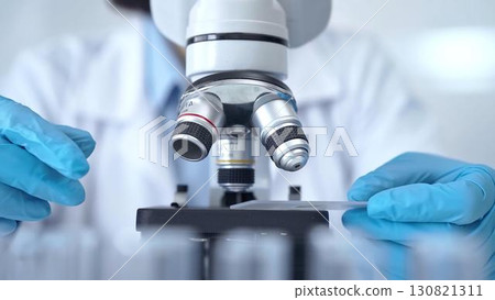 Scientist using microscope in laboratory. Close-up of a researcher's hands adjusting a modern microscope in a lab setting 130821311