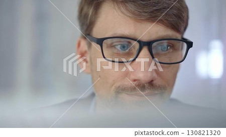 Businessman with glasses looking intently obscured partially by a translucent surface of laptop. Business people concept Businessman with glasses looking intently obscured partially by a translucent surface of laptop. Business people concept 130821320