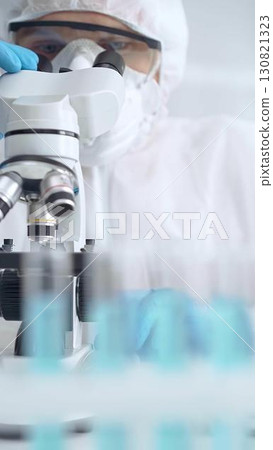 Scientist in ppe analyzing samples and analyzing samples with a microscope in a laboratory setting 130821323
