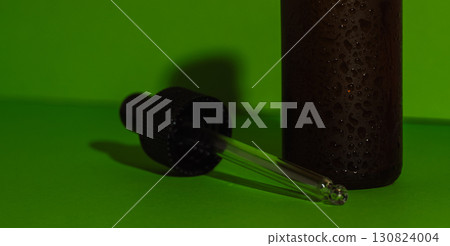 Cosmetic bottle with dropper and shadow on green background  130824004