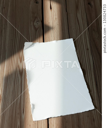 A blank white paper with torn edges is placed on a wooden surface, ready for use. 130824733