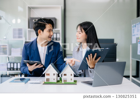 Balancing the property sector The real estate agent is explaining the house style to see the house design and the purchase agreement. model house Balancing the property sector The real estate agent is explaining the house style to see the house design and the purchase agreement. model house 130825351