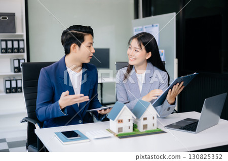 Balancing the property sector The real estate agent is explaining the house style to see the house design and the purchase agreement. model house Balancing the property sector The real estate agent is explaining the house style to see the house design and the purchase agreement. model house 130825352
