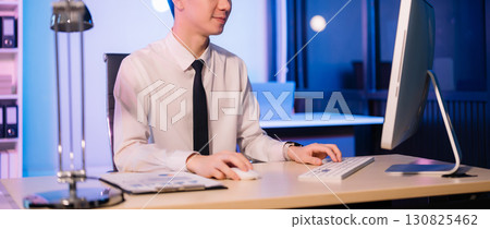 Businessman drinking coffee to get some energy for working overtime sitting at desk using computer and doing overtime 130825462