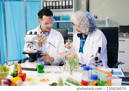 Team Asian scientists in a lab conducting food research using a microscope and lab equipment, showcasing innovation 130826079