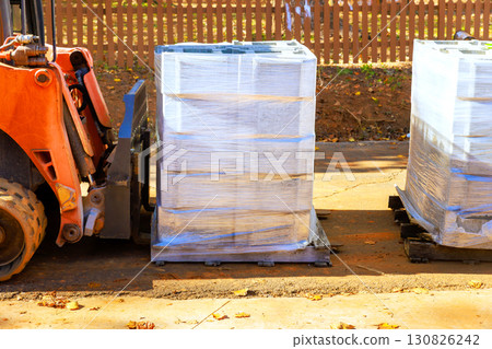 Forklift transporting wrapped cement block pallets in construction site under works day 130826242