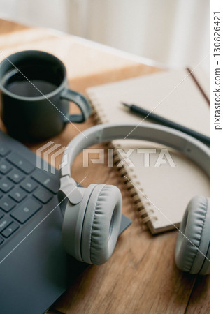 A workspace with a laptop, headphones, notebooks and coffee A workspace with a laptop, headphones, notebooks and coffee 130826421