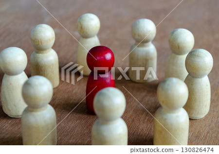 A red figurine alone against beige figurines illustrating imbalance that may reflect leadership or harassment 130826474