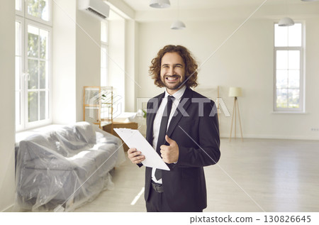 Portrait of friendly young male realtor showing thumbs up recommending his real estate agency. Portrait of friendly young male realtor showing thumbs up recommending his real estate agency. 130826645