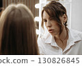 Makeup artist working on creating look for model. Focused look of makeup artist 130826845
