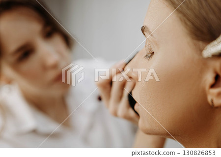 Make-up artist at work. Applying make-up to model face. Make-up artist at work. Applying make-up to model face. 130826853
