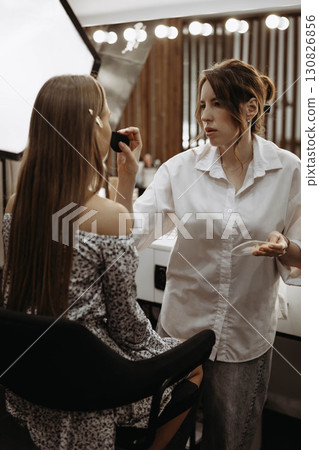 Makeup artist works with model to create an image. Preparing model skin Makeup artist works with model to create an image. Preparing model skin 130826856