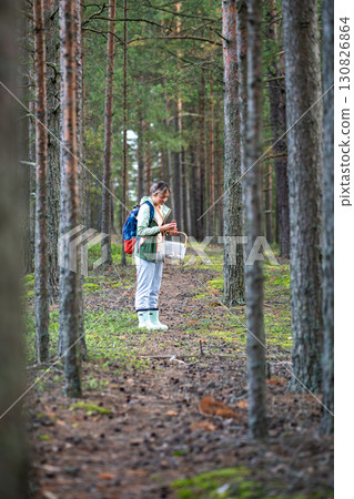 Satisfied woman check freshly picked mushroom for edibility in pine forest during foraging walk Satisfied woman check freshly picked mushroom for edibility in pine forest during foraging walk 130826864