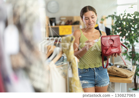 Happy young woman choosing handbag in clothing store Happy young woman choosing handbag in clothing store 130827065