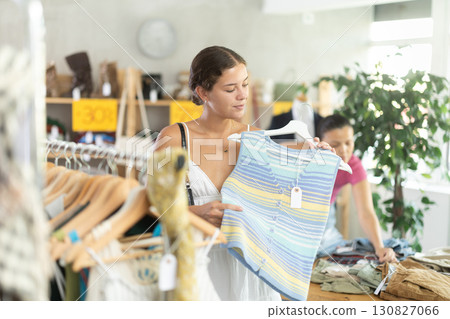 Positive joyful woman looking for fashionable clothes in clothing boutique Positive joyful woman looking for fashionable clothes in clothing boutique 130827066