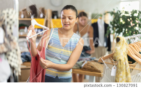 Positive joyful woman looking for fashionable clothes in clothing boutique 130827091