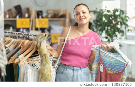 Positive asian woman choosing something for summer in clothing store Positive asian woman choosing something for summer in clothing store 130827103