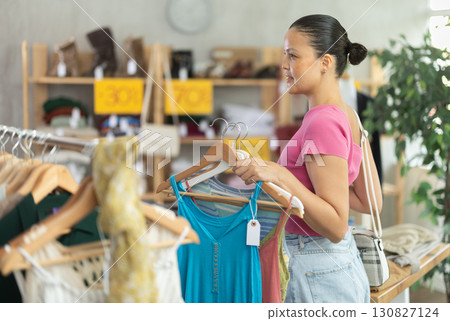 Positive asian woman choosing something for summer in clothing store 130827124