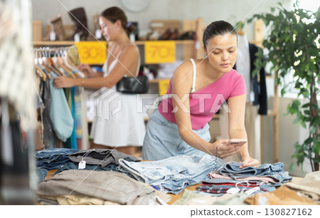 Female shopper checks the quality of jeans or shorts using QR code on label 130827162