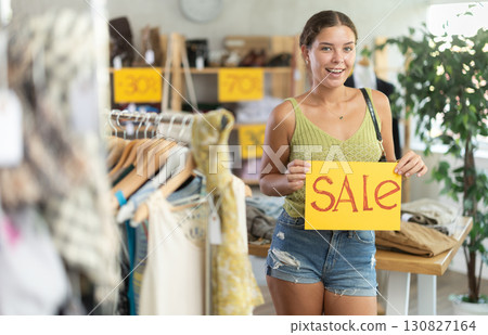 Happy woman holding a sign saying Sale in the interior of fashion store 130827164