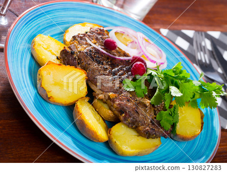 Beef steak with baked potatoes and sauce at plate with greens 130827283