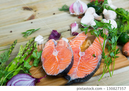 Raw salmon steaks with fresh vegetables and mushrooms on wooden desk 130827357