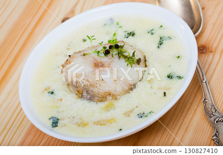 Boiled creamy soup with white fish pollock and greens at plate Boiled creamy soup with white fish pollock and greens at plate 130827410