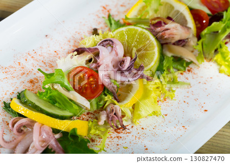 Salad of of boiled squids with lemon and fresh mix salad at plate 130827470