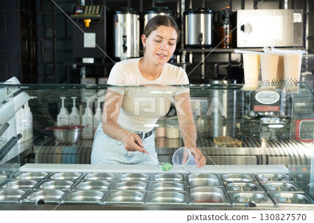 Positive saleswoman inviting to try aromatic bubble tea 130827570