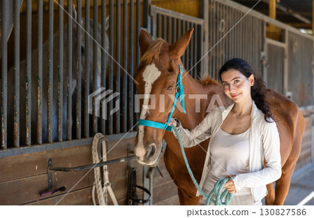 Young woman leads horse out of stable Young woman leads horse out of stable 130827586
