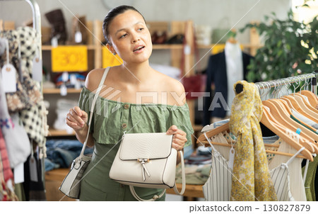 Happy young Asian woman choosing handbag in clothing store 130827879