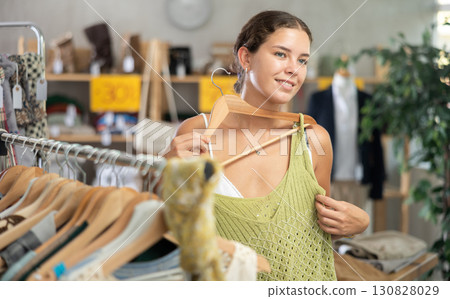 Positive young woman choosing something for summer in clothing store Positive young woman choosing something for summer in clothing store 130828029