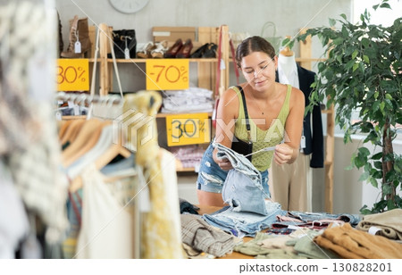 Positive young woman choosing pantaloons in clothing store Positive young woman choosing pantaloons in clothing store 130828201