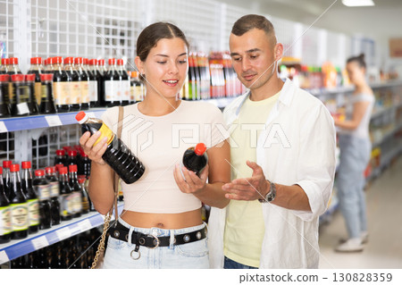 Smiling couple choosing soy sauce at Asian grocery store 130828359