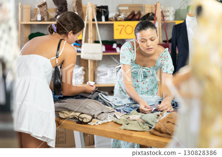 Women customers turn over and choose trousers or shorts in store Women customers turn over and choose trousers or shorts in store 130828386