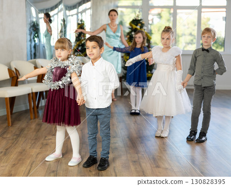 Christmas ball - group of children in festive clothes dances a waltz around New Year tree Christmas ball - group of children in festive clothes dances a waltz around New Year tree 130828395