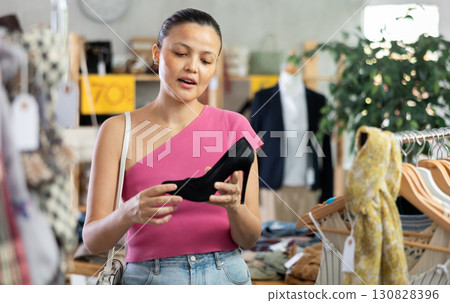 Beautiful asian woman chooses fashionable shoes in prestigious store 130828396