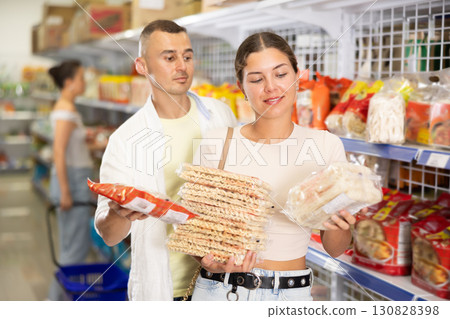 Friendly young couple choosing Asian noodles at grocery store 130828398