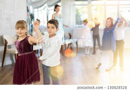 Enthusiastic preteen children dancing waltz in pairs in dance school 130828528