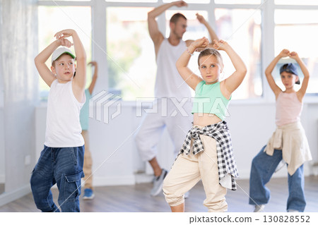 Active children stand in row during hip-hop dance classes under guidance of male trainer in sports studio Active children stand in row during hip-hop dance classes under guidance of male trainer in sports studio 130828552