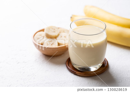 Banana milk in glass with sliced banana and fruit on white background 130828619