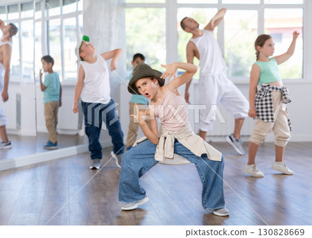 Happy young girl and boy in casual clothes performing hip hop dance in dancing room during training with male teacher 130828669