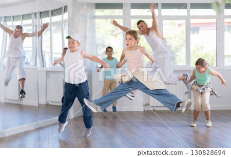Group of children dance hip-hop with dance teacher. Rehearsing jumps Group of children dance hip-hop with dance teacher. Rehearsing jumps 130828694