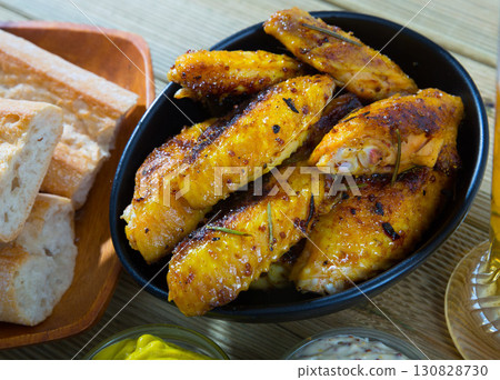 Fried chicken wings served in black bowl, two sauses and bread 130828730