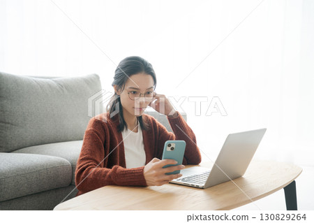 A woman operating a computer in the living room A woman operating a computer in the living room 130829264
