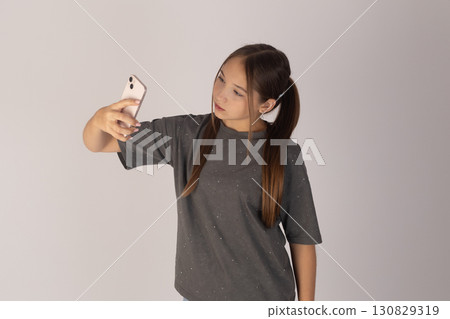 a young woman with long dark hair tied in pigtails, wearing a grey t-shirt, and a young woman with long dark hair tied in pigtails, wearing a grey t-shirt, and 130829319