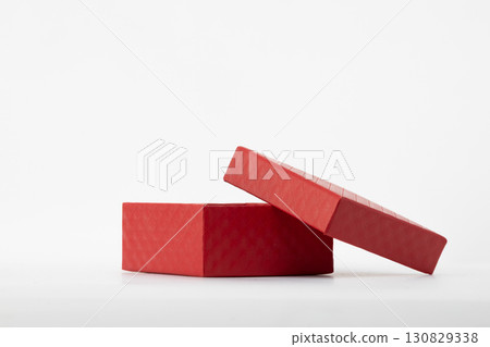 a red gift box with its lid partially open, resting on a light-colored surface 130829338