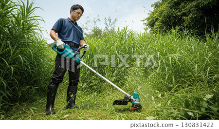 Male worker mowing the grass with a lawnmower 130831422